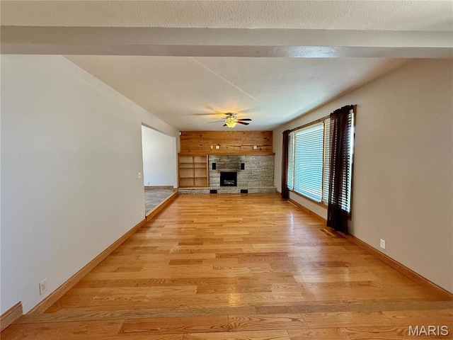 unfurnished living room featuring a fireplace, ceiling fan, light wood-style flooring, and baseboards