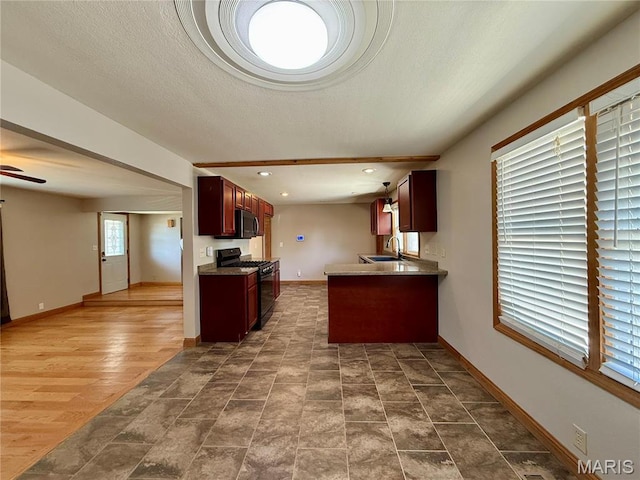 kitchen with black range with gas cooktop, a sink, baseboards, open floor plan, and recessed lighting