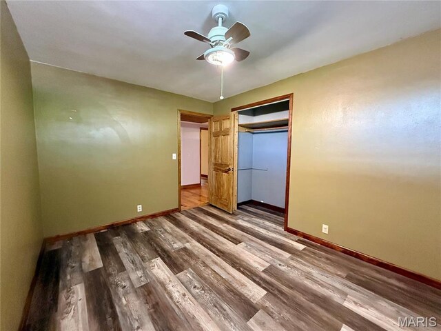unfurnished bedroom with baseboards, wood finished floors, ceiling fan, and a closet