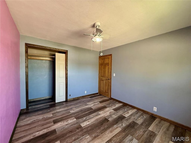 unfurnished bedroom featuring dark wood finished floors, baseboards, a closet, and ceiling fan