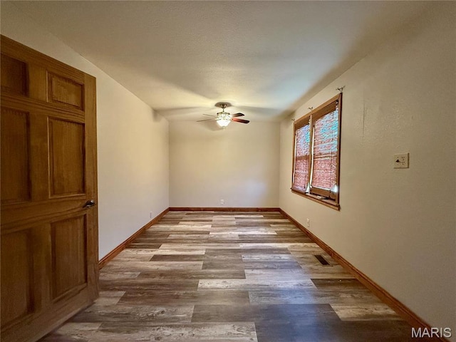 empty room featuring ceiling fan, wood finished floors, and baseboards