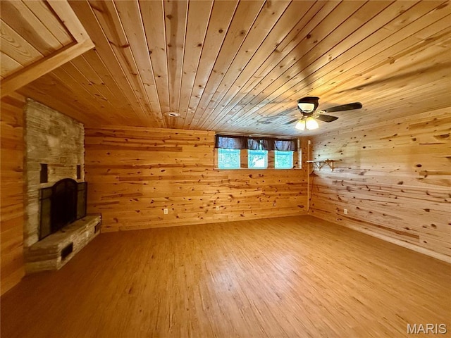unfurnished living room with wooden walls, wood ceiling, wood finished floors, a fireplace, and ceiling fan
