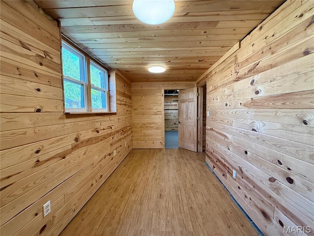 hallway featuring wood walls, wooden ceiling, and light wood-style flooring