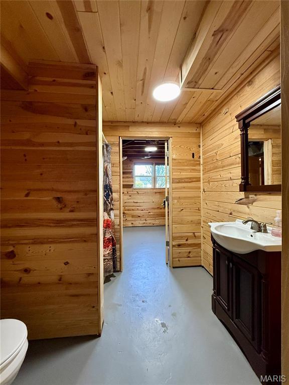 full bathroom with wood ceiling, finished concrete floors, vanity, wooden walls, and toilet
