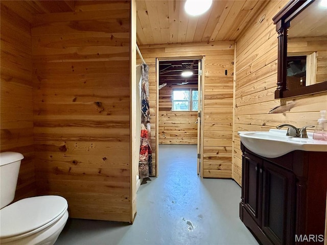 bathroom with wood walls, wooden ceiling, finished concrete flooring, vanity, and toilet