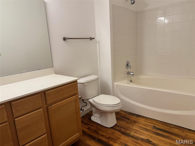 bathroom with toilet, wood finished floors, shower / bath combination, and vanity