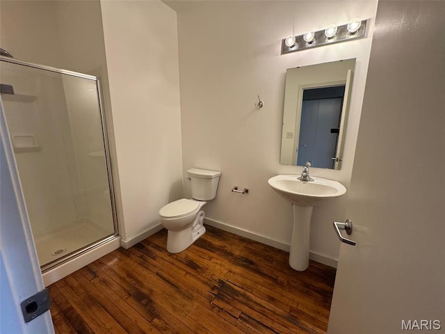 full bath featuring a stall shower, toilet, wood finished floors, and baseboards