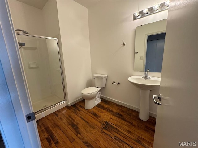 bathroom featuring a stall shower, hardwood / wood-style floors, toilet, baseboards, and a sink