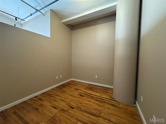 unfurnished room with hardwood / wood-style flooring and baseboards