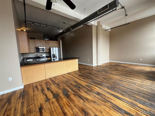 kitchen with appliances with stainless steel finishes, dark countertops, open floor plan, and ceiling fan