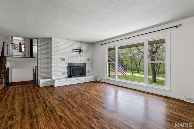 10179 Cherry Hill Ln, Potosi, MO 63664 - unfurnished living room with a textured ceiling, wood finished floors, a brick fireplace, and baseboards