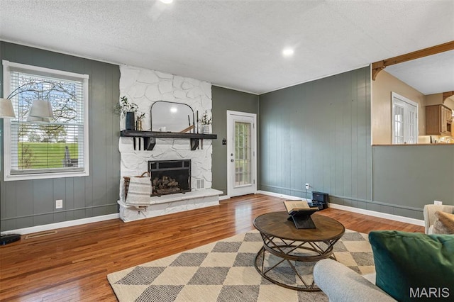 1304 Napoleon Dr, Bonne Terre, MO 63628 - living area featuring wood finished floors, baseboards, a fireplace, a textured ceiling, and a decorative wall