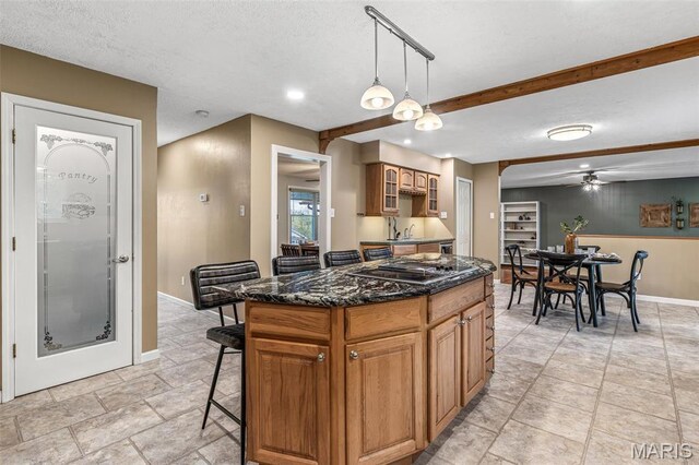1304 Napoleon Dr, Bonne Terre, MO 63628 - kitchen with a kitchen bar, a ceiling fan, baseboards, stovetop with downdraft, and decorative light fixtures