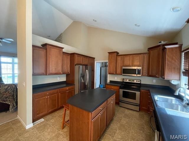 11 Summers Dr, Hawk Point, MO 63349 - kitchen featuring appliances with stainless steel finishes, a sink, dark countertops, a kitchen island, and brown cabinets
