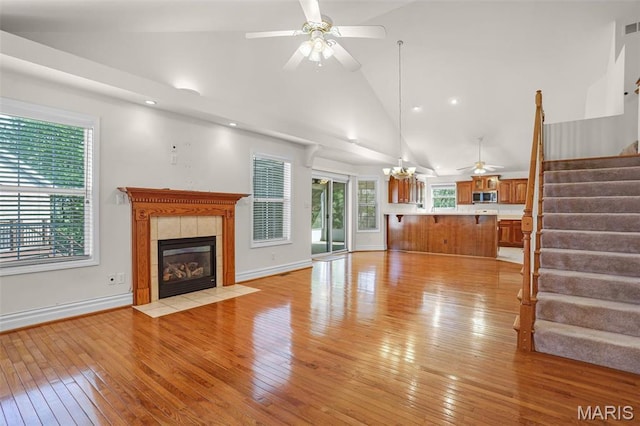 14 Berry Patch Ln, Glen Carbon, IL 62034 - unfurnished living room with ceiling fan, stairway, high vaulted ceiling, a tile fireplace, and light wood-type flooring