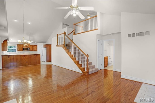 14 Berry Patch Ln, Glen Carbon, IL 62034 - unfurnished living room featuring light wood-style flooring, high vaulted ceiling, ceiling fan, a sink, and stairway