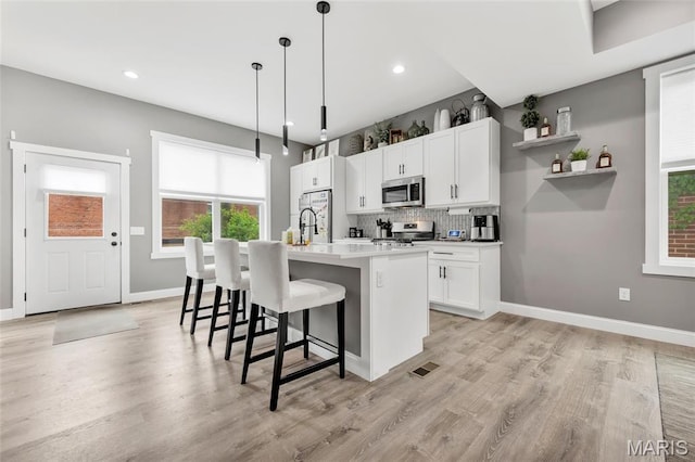 2034 Ann Ave, Saint Louis, MO 63104 - kitchen featuring stainless steel appliances, a kitchen island with sink, decorative backsplash, light wood-style flooring, and recessed lighting