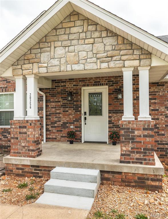 20256 Hardcastle Ln, Saint Robert, MO 65584 - view of exterior entry featuring a porch, stone siding, and brick siding