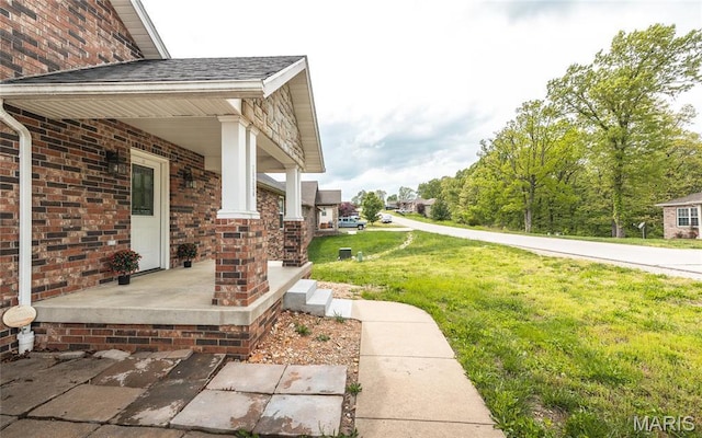 20256 Hardcastle Ln, Saint Robert, MO 65584 - view of side of home with covered porch, a lawn, and brick siding