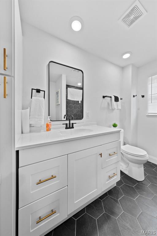 1326 Graham St, Saint Louis, MO 63139 - bathroom featuring toilet, vanity, tile patterned floors, and a shower