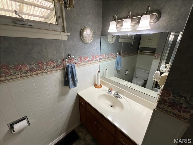 805 Willoway Ave, East Alton, IL 62024 - bathroom featuring wallpapered walls, wainscoting, toilet, vanity, and tile walls