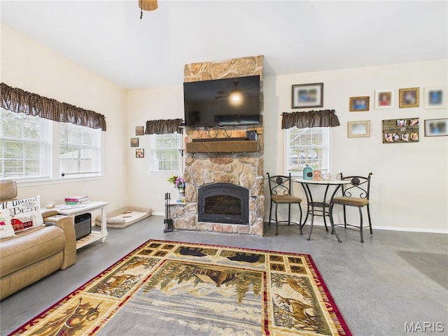 living area featuring concrete floors, a stone fireplace, and baseboards