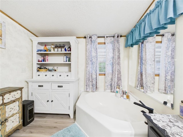 full bathroom featuring wood finished floors, a garden tub, and a textured ceiling