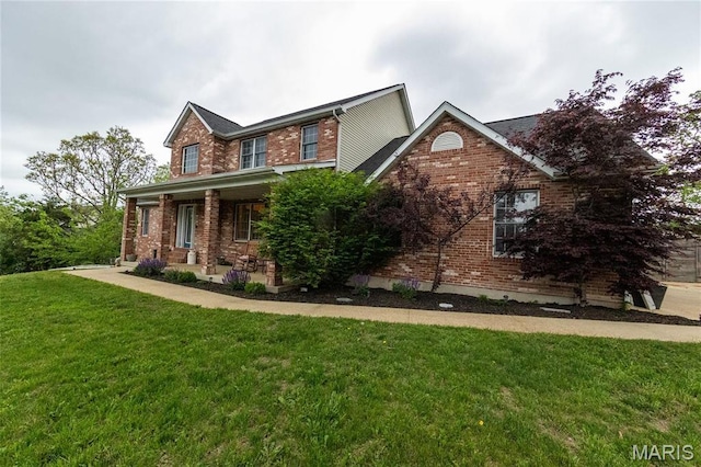 view of front of property featuring brick siding, a front lawn, and covered porch
