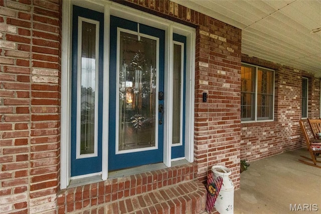 entrance to property with covered porch and brick siding