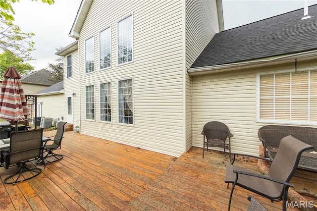 deck featuring central AC unit and outdoor dining space