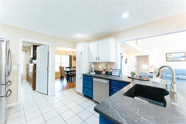 kitchen featuring stainless steel appliances, a sink, white cabinetry, a chandelier, and light tile patterned flooring