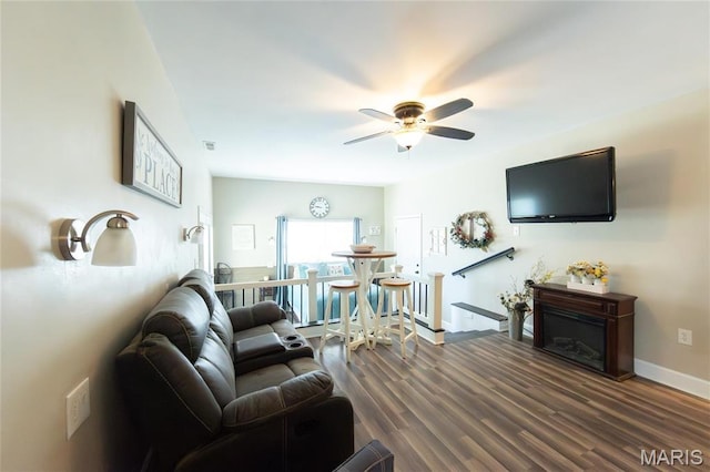 living area with a ceiling fan, wood finished floors, and baseboards