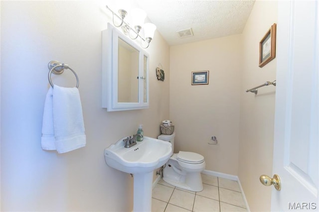 half bath featuring tile patterned floors, toilet, and a textured ceiling