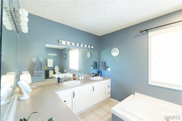 bathroom with tile patterned flooring, a textured ceiling, a tub to relax in, and double vanity