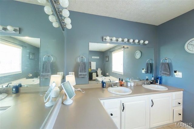 full bath featuring a bathtub, a textured ceiling, and double vanity