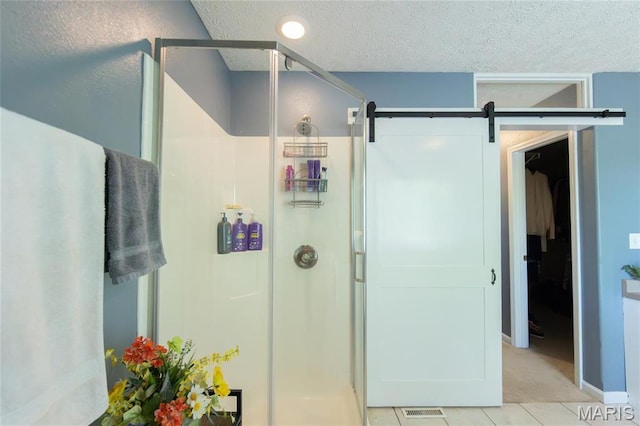 full bathroom featuring a shower stall, a textured ceiling, and tile patterned floors