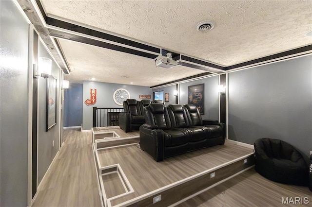 home theater with a textured ceiling, wood finished floors, baseboards, and beamed ceiling