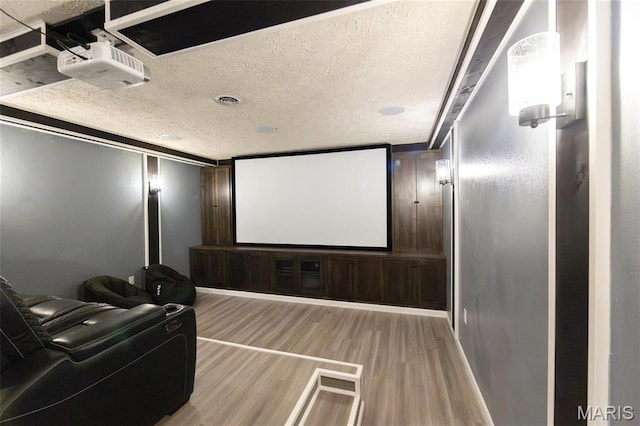 cinema featuring light wood-type flooring and a textured ceiling