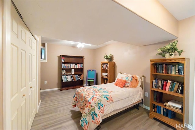 bedroom with wood finished floors, baseboards, and a closet
