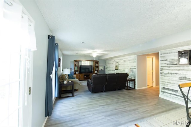 living area with a textured ceiling, light wood-type flooring, and baseboards
