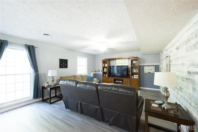 living room featuring wood finished floors, a textured ceiling, a ceiling fan, and baseboards