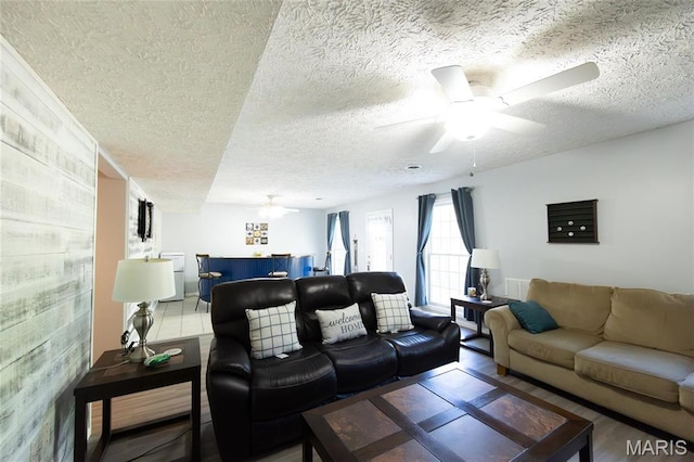 living room featuring a textured ceiling, a ceiling fan, and wood finished floors