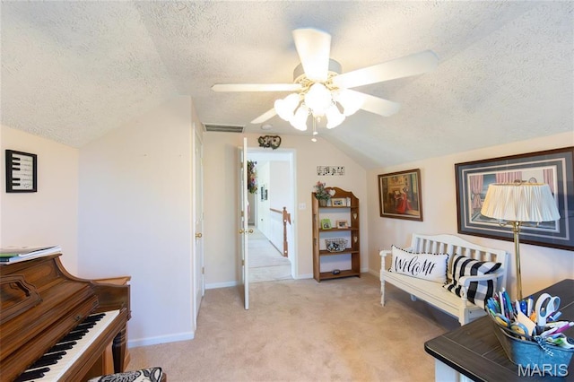 sitting room featuring a textured ceiling, lofted ceiling, light carpet, ceiling fan, and baseboards