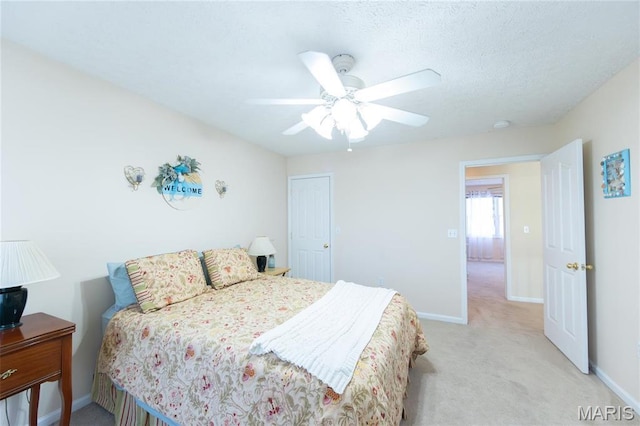 bedroom featuring light carpet, baseboards, ceiling fan, and a textured ceiling