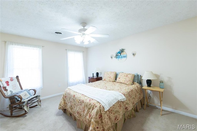bedroom featuring light carpet, baseboards, a ceiling fan, and a textured ceiling