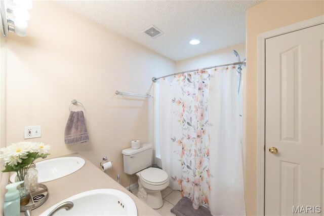 bathroom with a sink, tile patterned floors, toilet, a shower with curtain, and a textured ceiling