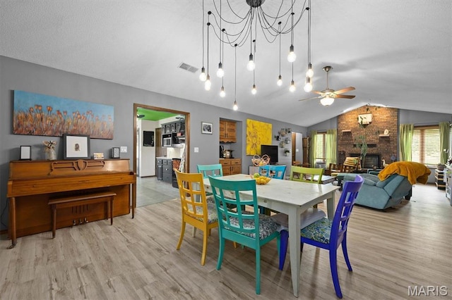 dining space with lofted ceiling, wood finished floors, ceiling fan, and a fireplace