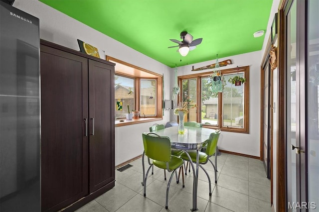 dining area featuring a ceiling fan, light tile patterned floors, and baseboards
