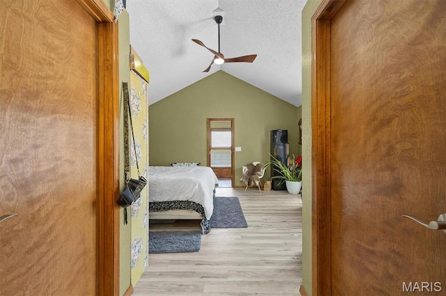 bedroom featuring wood finished floors, vaulted ceiling, a textured ceiling, and a ceiling fan