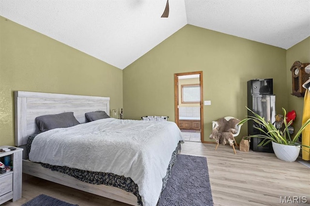 bedroom with lofted ceiling, wood finished floors, connected bathroom, and a ceiling fan